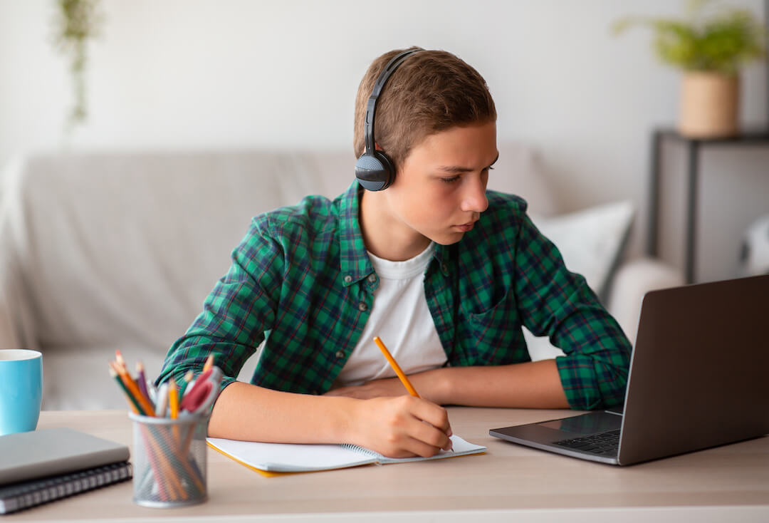 pensive-school-boy-with-earphones-studying-online--XXEV6ED