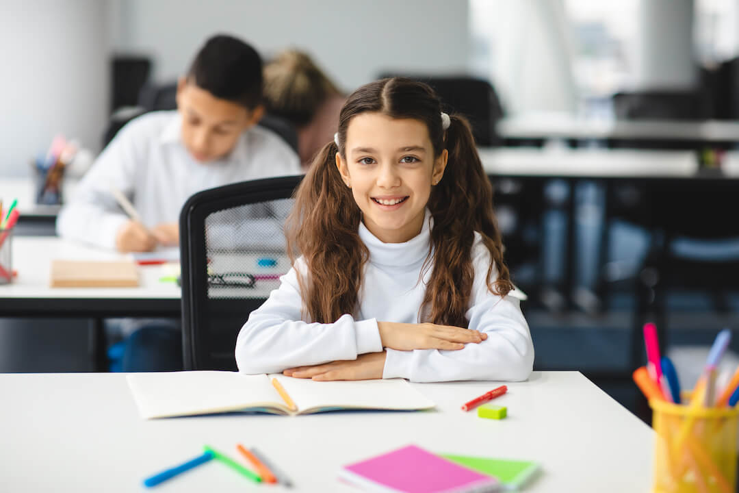 portrait-of-small-girl-sitting-at-desk-in-classroo-2021-09-02-05-06-44-utc