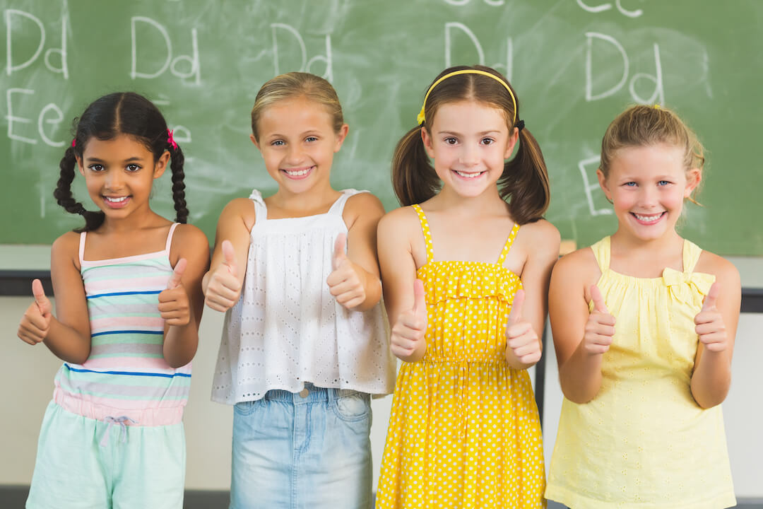 smiling-kids-showing-thumbs-up-in-classroom-2021-08-28-18-10-36-utc-2