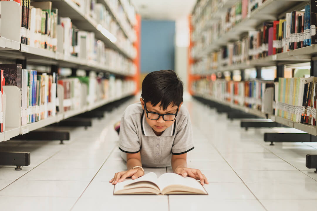 smart-school-boy-reading-a-book-at-the-library-2022-09-28-22-48-33-utc-2