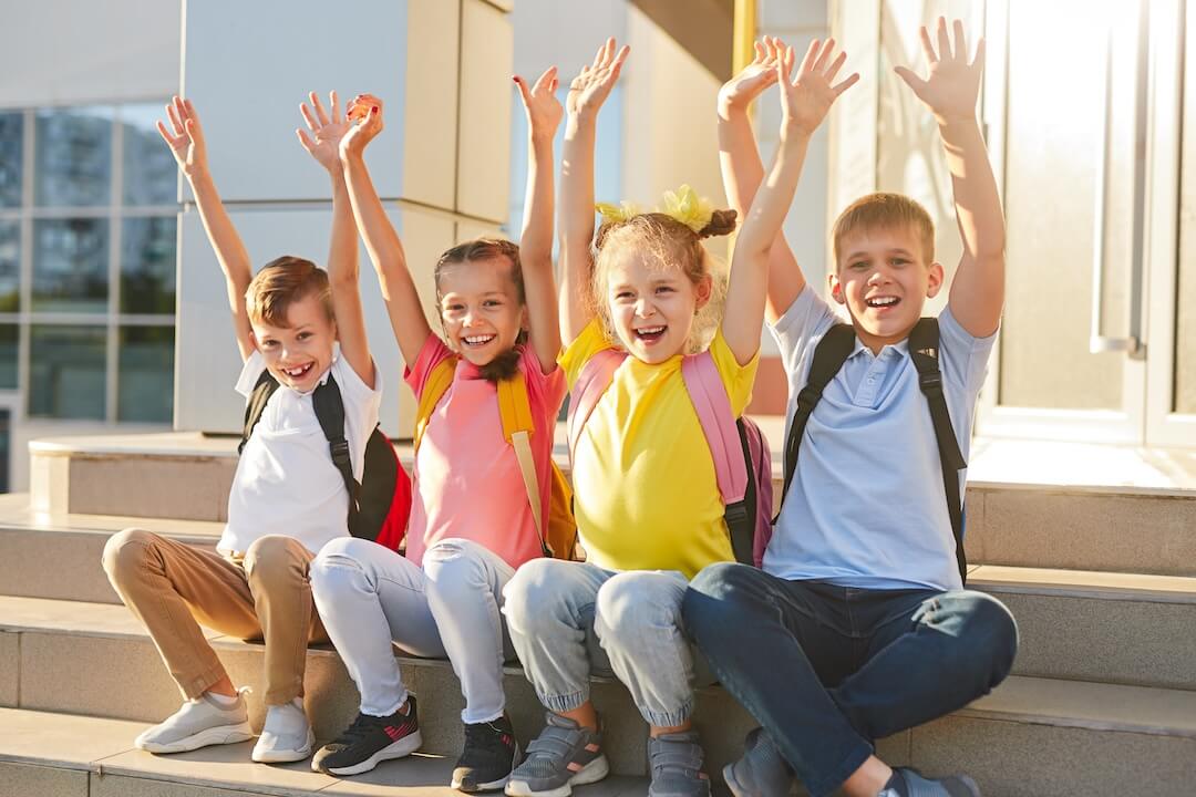 happy-kids-sitting-on-school-steps-2023-11-27-05-33-24-utc-2